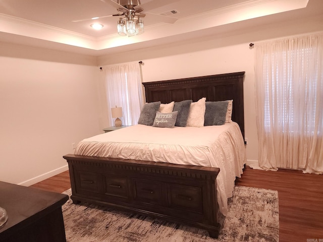 bedroom featuring hardwood / wood-style flooring, ceiling fan, crown molding, and a tray ceiling