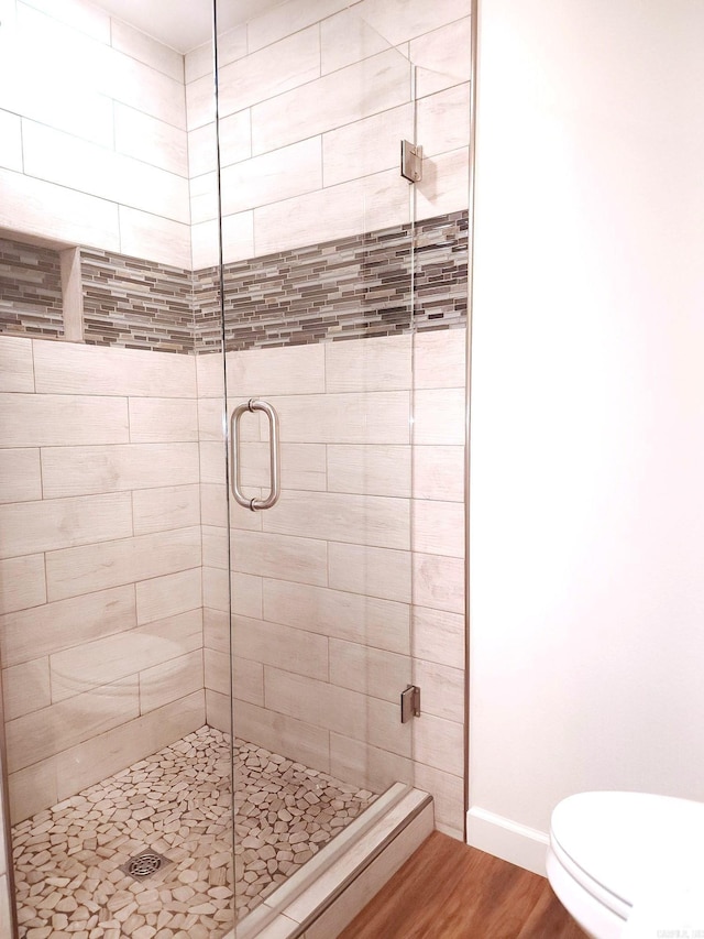 bathroom with a shower with door, wood-type flooring, and toilet