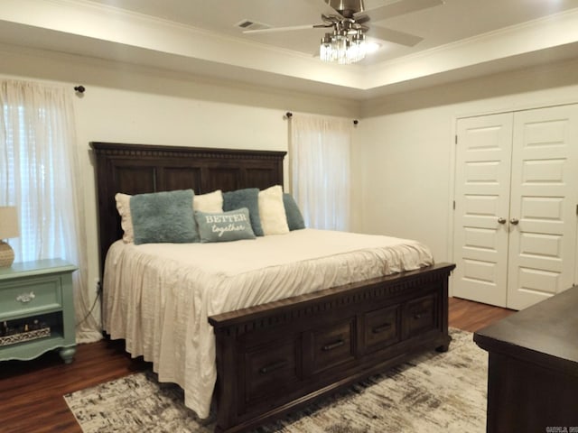 bedroom featuring ceiling fan, dark hardwood / wood-style flooring, crown molding, and a closet