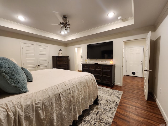 bedroom featuring ornamental molding, a tray ceiling, ceiling fan, dark hardwood / wood-style floors, and a closet