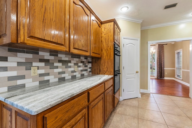 kitchen with decorative backsplash, light tile patterned flooring, light stone countertops, and ornamental molding