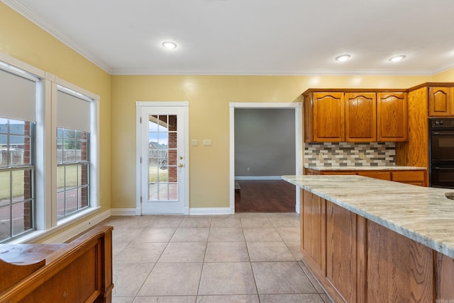 kitchen featuring tasteful backsplash, light stone counters, ornamental molding, double oven, and light tile patterned flooring