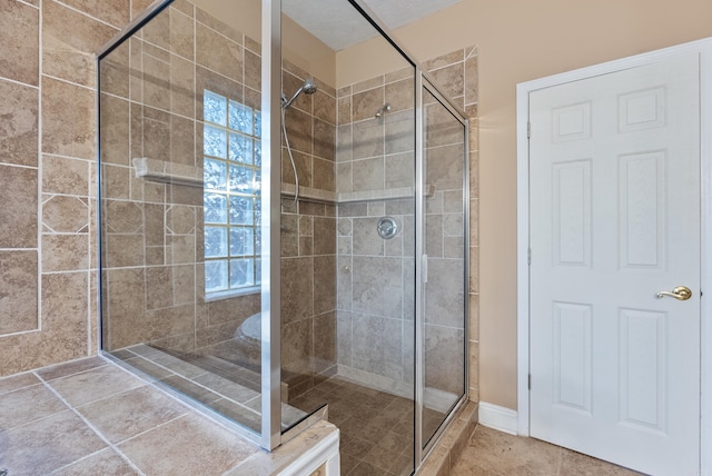 bathroom featuring a tile shower, a textured ceiling, and tile patterned floors