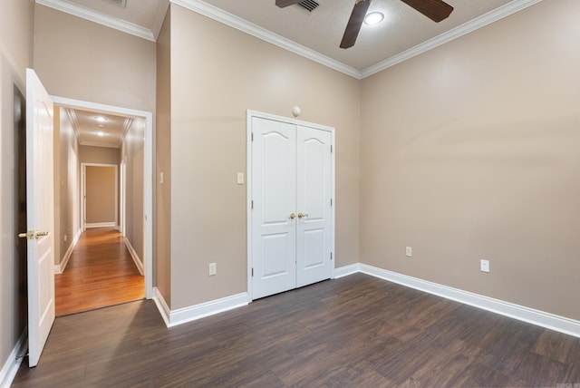 unfurnished bedroom with a closet, crown molding, ceiling fan, and dark wood-type flooring