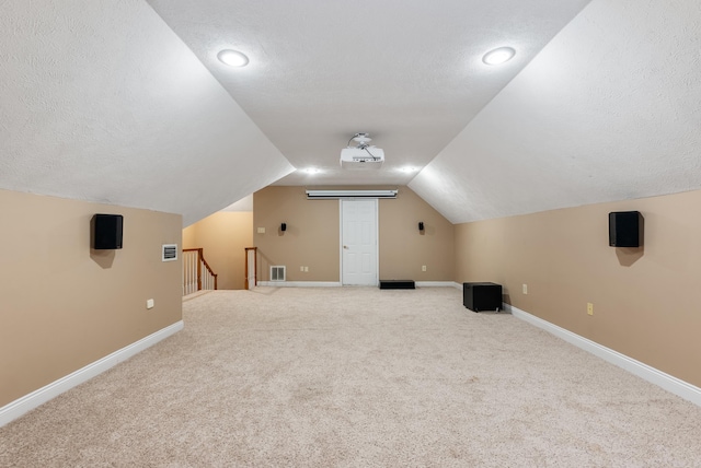 additional living space featuring a textured ceiling, lofted ceiling, and carpet floors