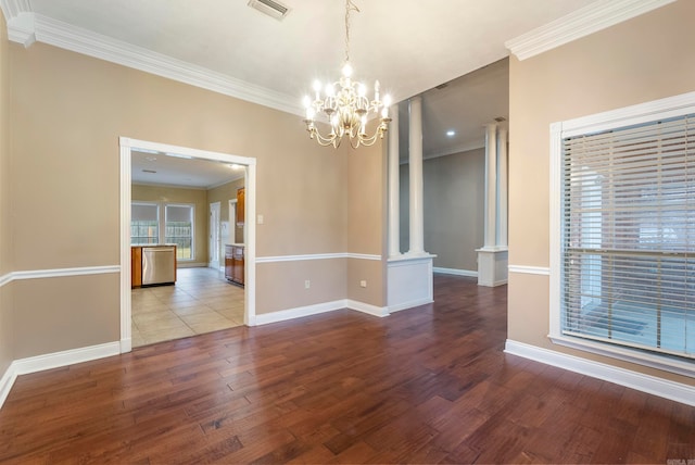 spare room with a chandelier, hardwood / wood-style flooring, decorative columns, and ornamental molding