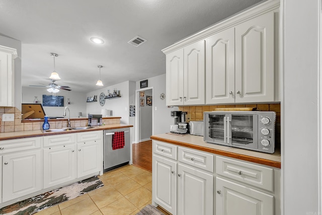 kitchen featuring backsplash, sink, hanging light fixtures, stainless steel dishwasher, and white cabinetry