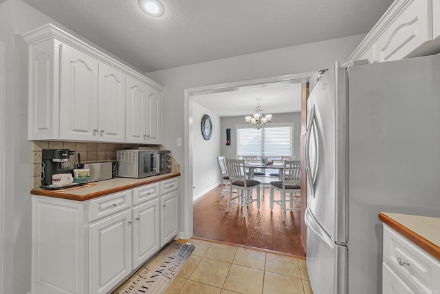 kitchen featuring pendant lighting, white cabinets, stainless steel appliances, and light tile patterned floors