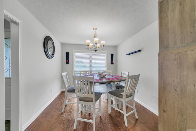 dining room featuring a chandelier, dark wood-type flooring, and a textured ceiling