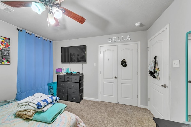 bedroom with a textured ceiling, a closet, light colored carpet, and ceiling fan