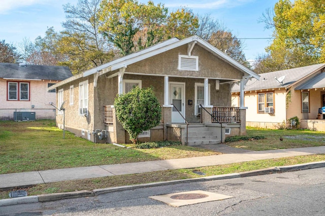 bungalow-style home featuring cooling unit, central AC, a front lawn, and a porch