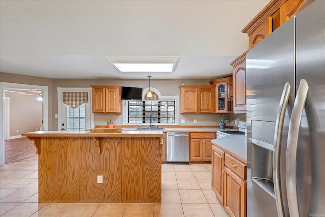 kitchen with light tile patterned floors, a center island, stainless steel appliances, and sink