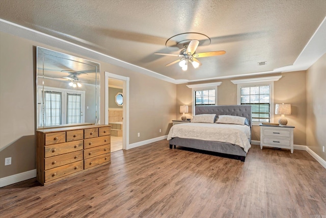 bedroom featuring ensuite bathroom, ceiling fan, wood-type flooring, and a textured ceiling