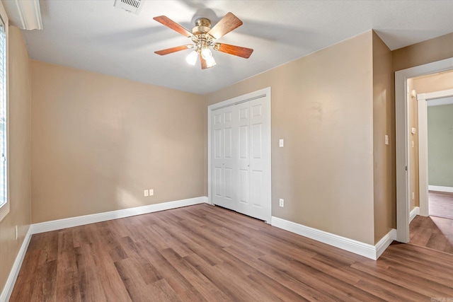 unfurnished bedroom featuring ceiling fan, a closet, and wood-type flooring