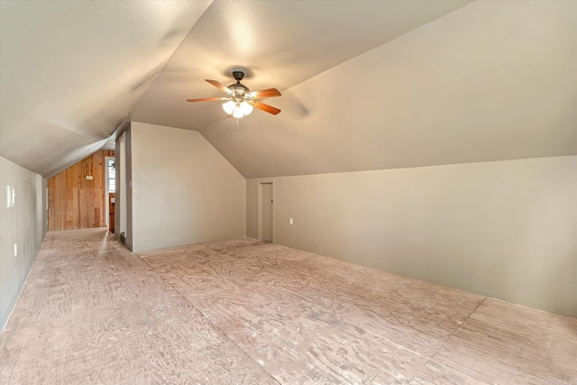 bonus room featuring ceiling fan, wood walls, and vaulted ceiling