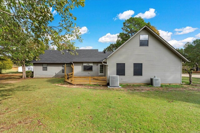 rear view of house with cooling unit, a deck, and a yard