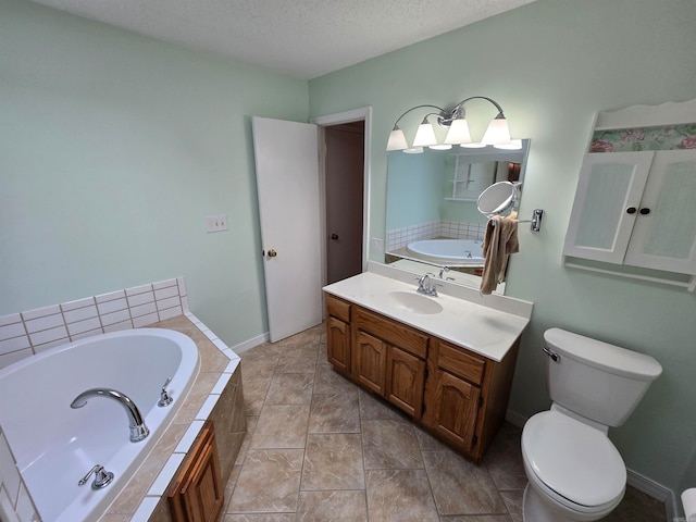 bathroom featuring tiled bath, vanity, a textured ceiling, and toilet