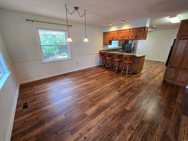 kitchen featuring ceiling fan, dark hardwood / wood-style flooring, kitchen peninsula, and a textured ceiling