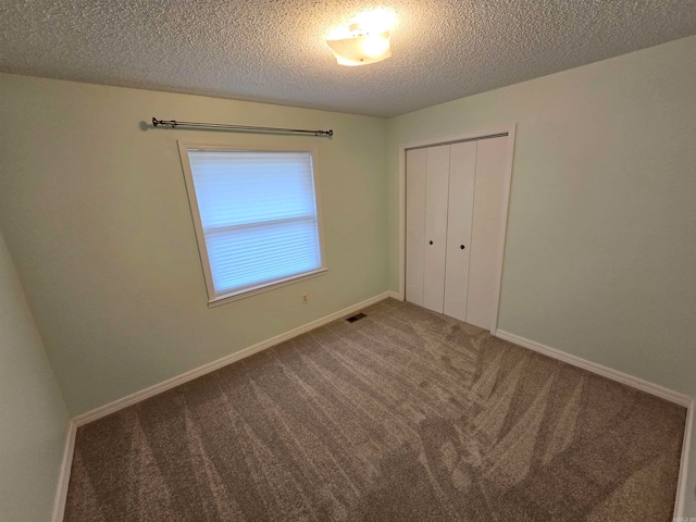 unfurnished bedroom with a textured ceiling, carpet floors, and a closet