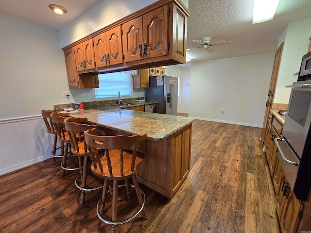 kitchen featuring dark wood-type flooring, high end refrigerator, ceiling fan, a textured ceiling, and kitchen peninsula