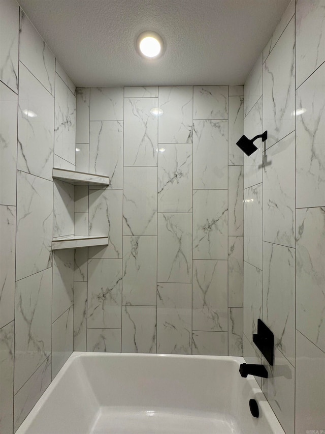 bathroom featuring tiled shower / bath combo and a textured ceiling