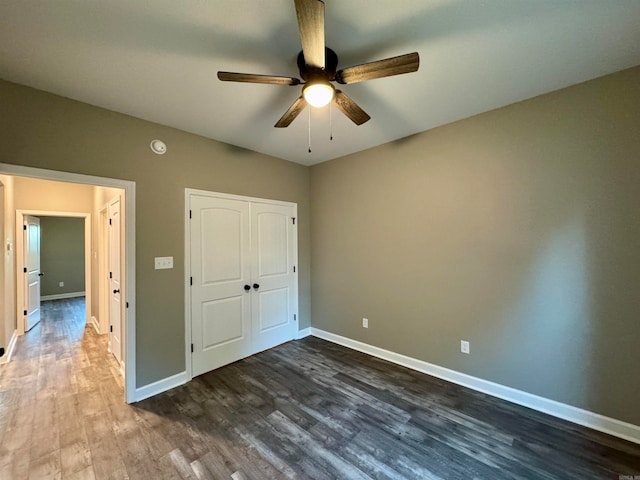 unfurnished bedroom with ceiling fan, dark hardwood / wood-style floors, and a closet