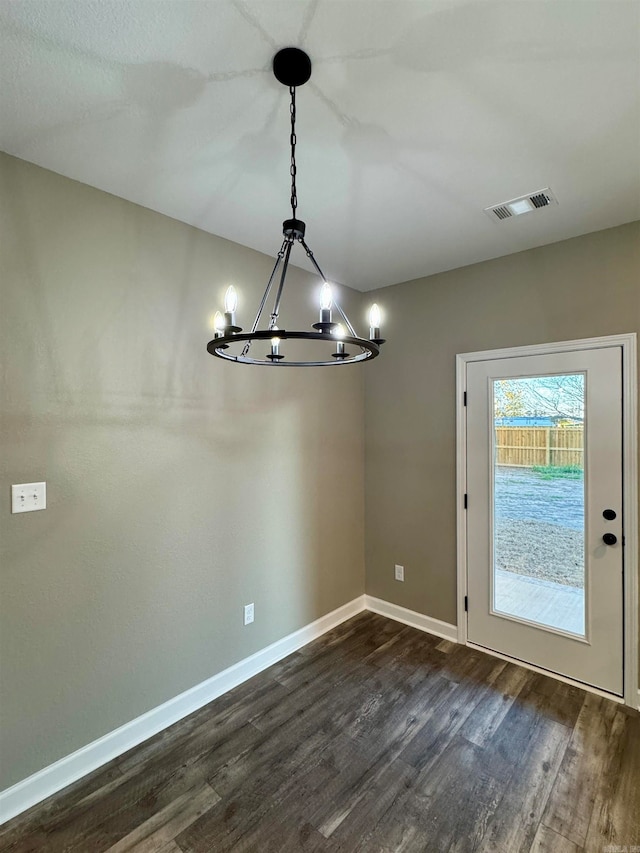 unfurnished dining area featuring a chandelier and dark wood-type flooring