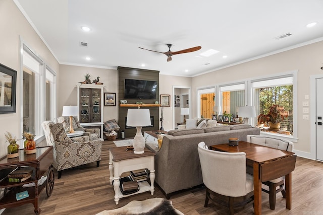 living room featuring wood-type flooring, ceiling fan, and ornamental molding