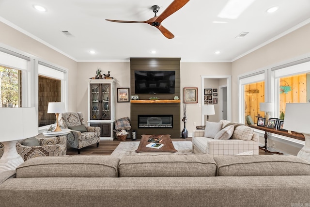 living room with ceiling fan, a fireplace, ornamental molding, and hardwood / wood-style flooring