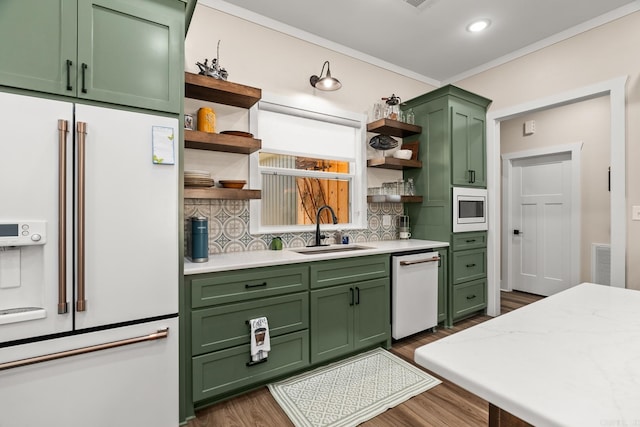 kitchen with sink, green cabinets, dark hardwood / wood-style flooring, backsplash, and white appliances