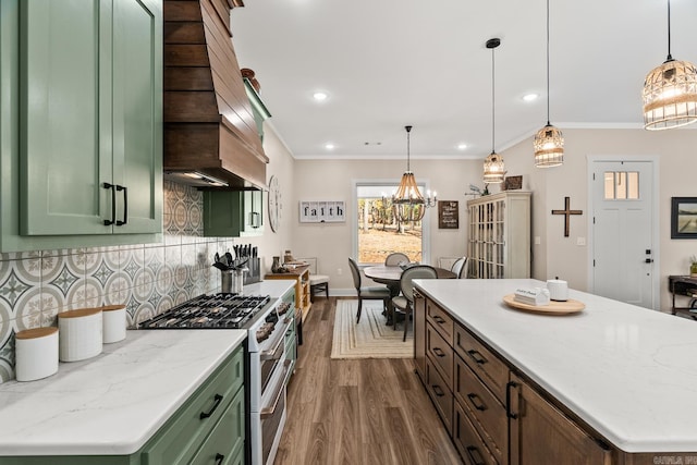 kitchen with high end stove, tasteful backsplash, hanging light fixtures, and green cabinetry