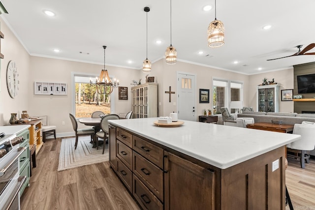 kitchen with ceiling fan with notable chandelier, crown molding, hanging light fixtures, light hardwood / wood-style flooring, and dark brown cabinets