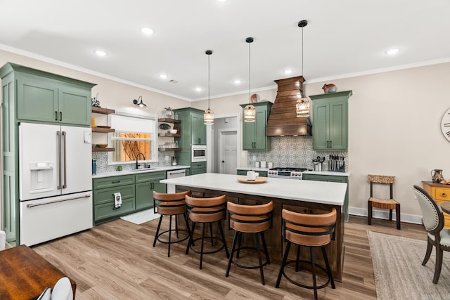 kitchen featuring premium range hood, stainless steel appliances, pendant lighting, light hardwood / wood-style floors, and green cabinets