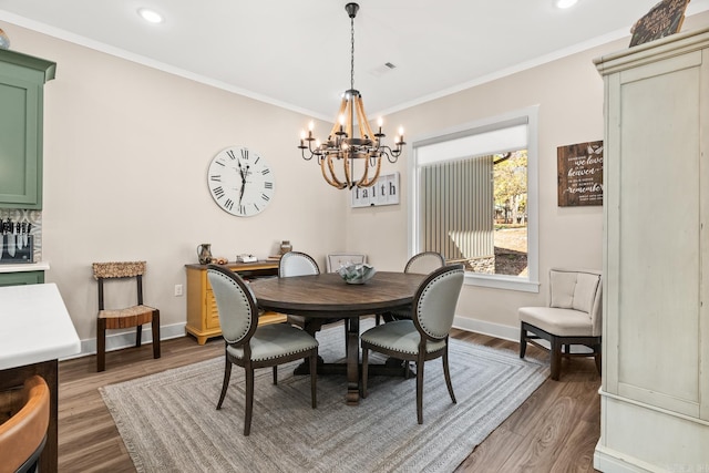 dining area featuring wood-type flooring, an inviting chandelier, and ornamental molding