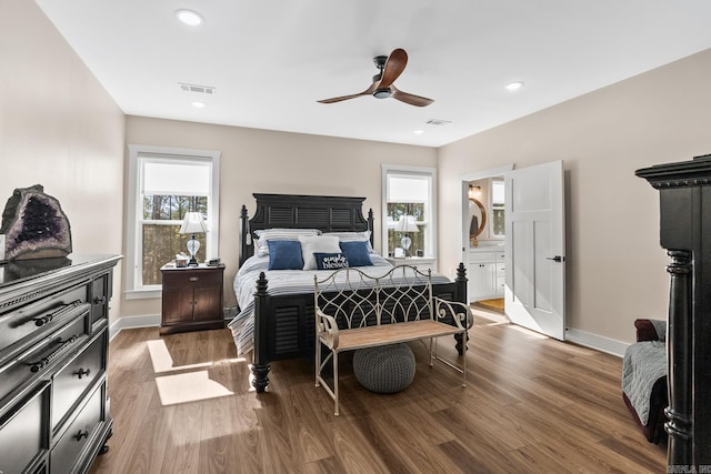 bedroom with multiple windows, ceiling fan, hardwood / wood-style floors, and ensuite bathroom