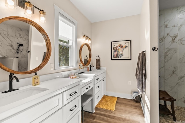 bathroom with a tile shower, vanity, and hardwood / wood-style flooring