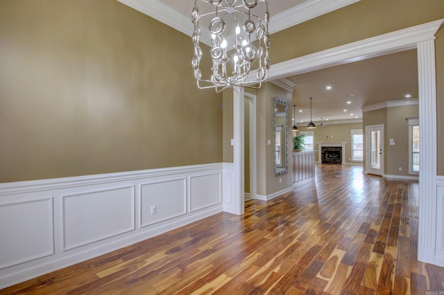 unfurnished dining area featuring crown molding, dark wood-type flooring, and a chandelier