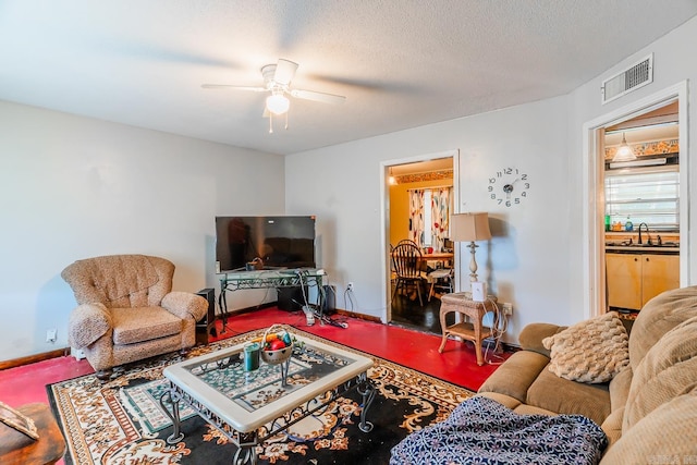 living room with ceiling fan, sink, and a textured ceiling