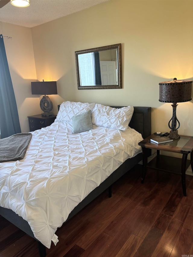 bedroom with dark hardwood / wood-style flooring and a textured ceiling