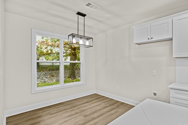 unfurnished dining area with a chandelier and light hardwood / wood-style flooring