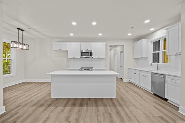 kitchen featuring a center island, white cabinetry, sink, and appliances with stainless steel finishes