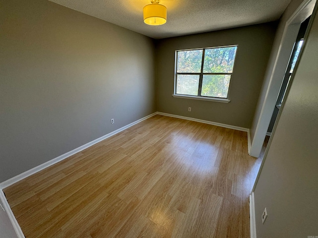 unfurnished room featuring a textured ceiling and light wood-type flooring