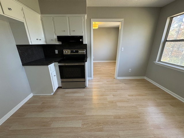 kitchen featuring white cabinets, backsplash, light hardwood / wood-style flooring, and stainless steel electric range oven