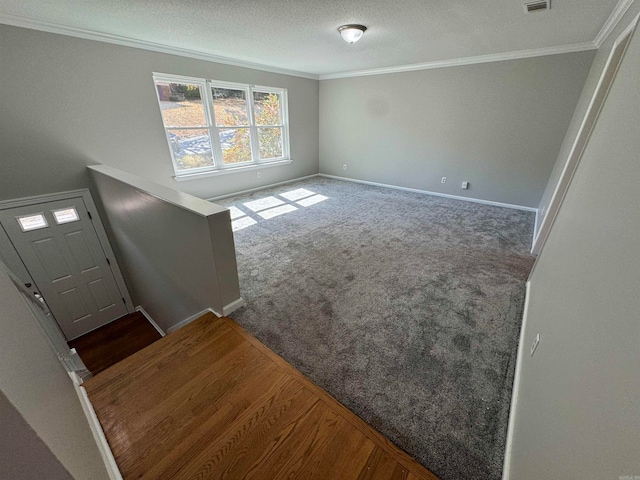 foyer entrance with crown molding, a textured ceiling, and dark colored carpet