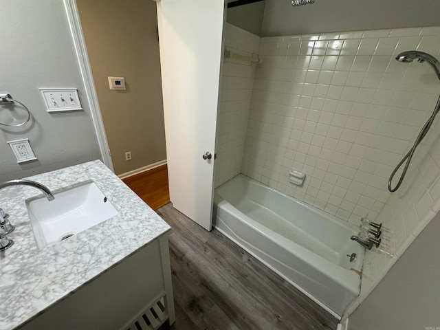 bathroom featuring wood-type flooring, vanity, and tiled shower / bath combo