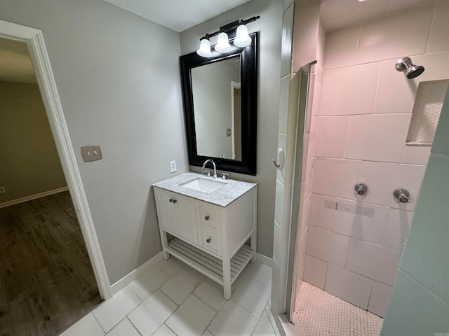 bathroom featuring vanity, wood-type flooring, and tiled shower