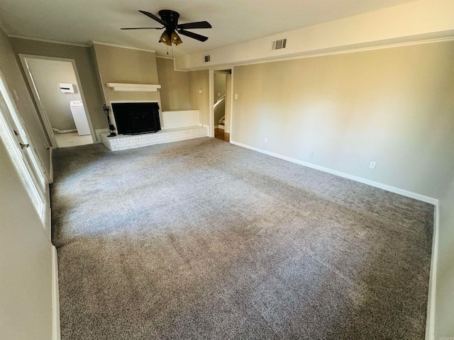 unfurnished living room with ceiling fan, a brick fireplace, washer / clothes dryer, carpet, and ornamental molding