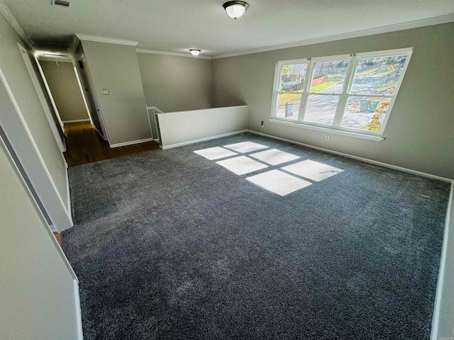 empty room featuring dark colored carpet, a textured ceiling, and ornamental molding