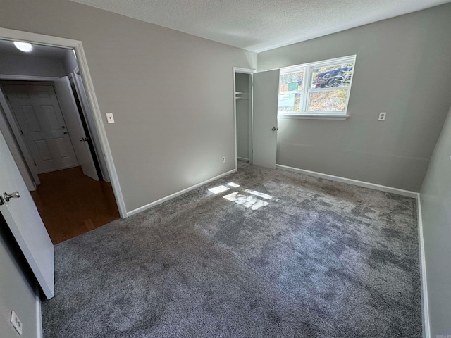 spare room featuring a textured ceiling and dark carpet