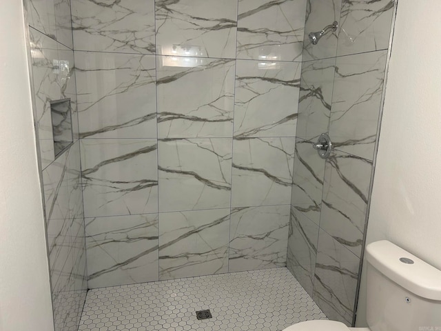 bathroom featuring a tile shower and toilet